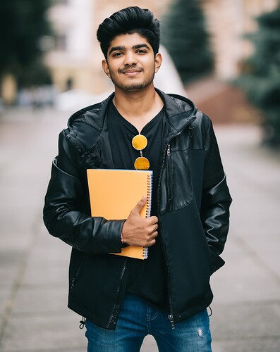 handsome-young-indian-student-man-holding-notebooks-while-standing-street